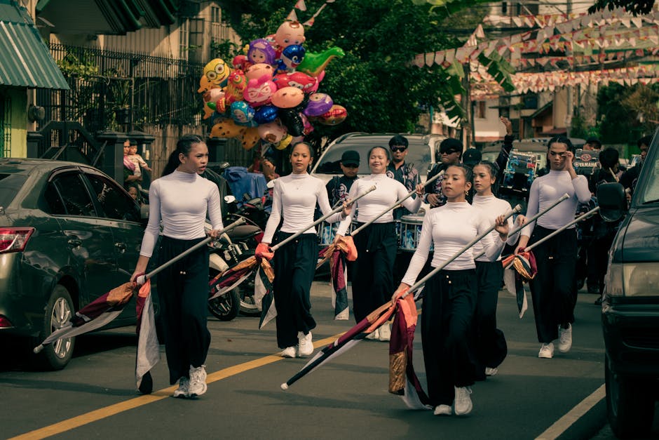 A colorful street parade featuring a color guard team marching with vibrant flags and balloons.