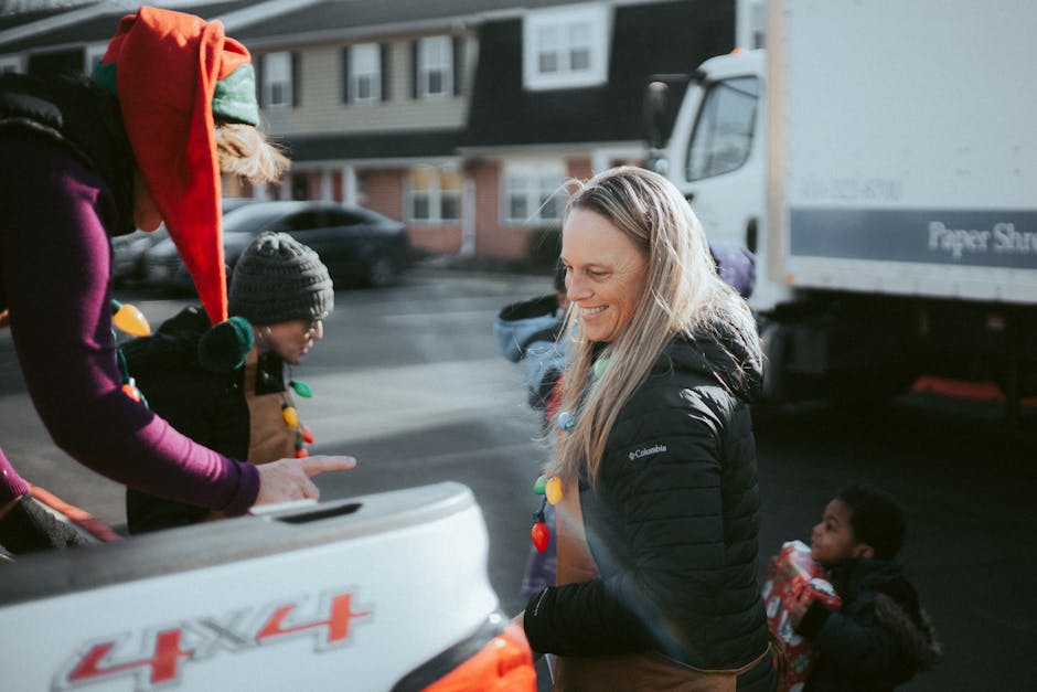 Volunteers in festive attire distribute gifts to children outdoors during holiday season.